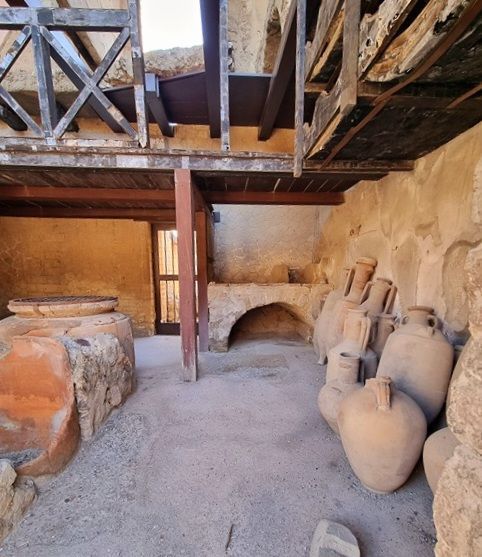 Interior de una tienda romana en Herculano con estanterías y recipientes de almacenamiento